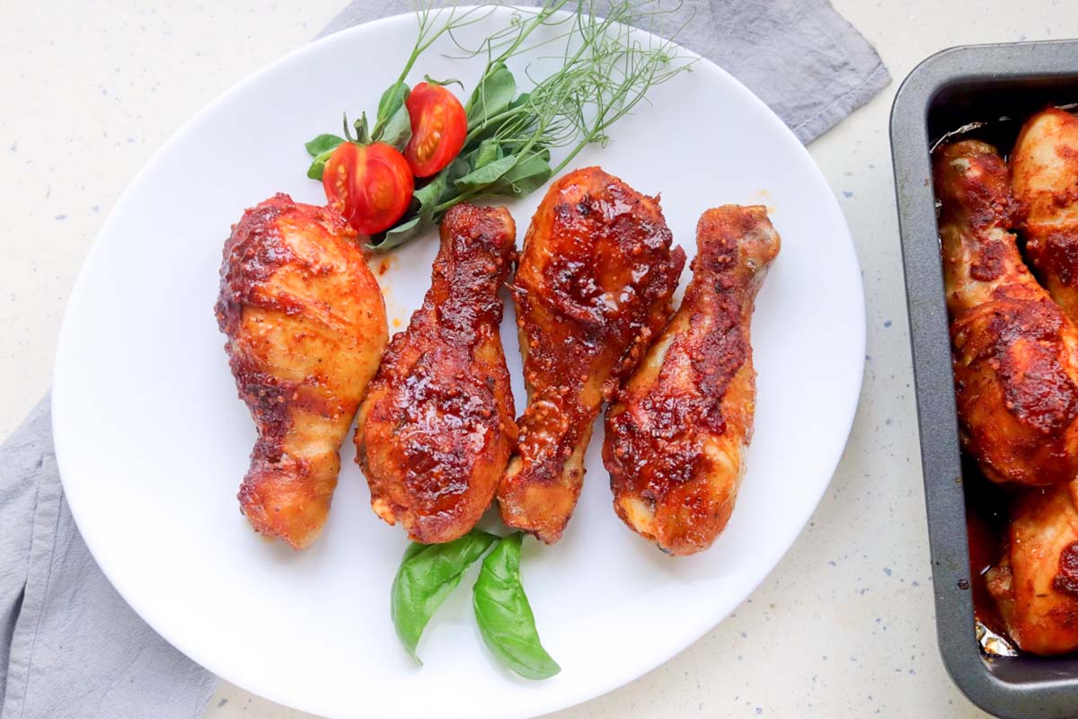 Drumsticks on a plate next to the baking dish.