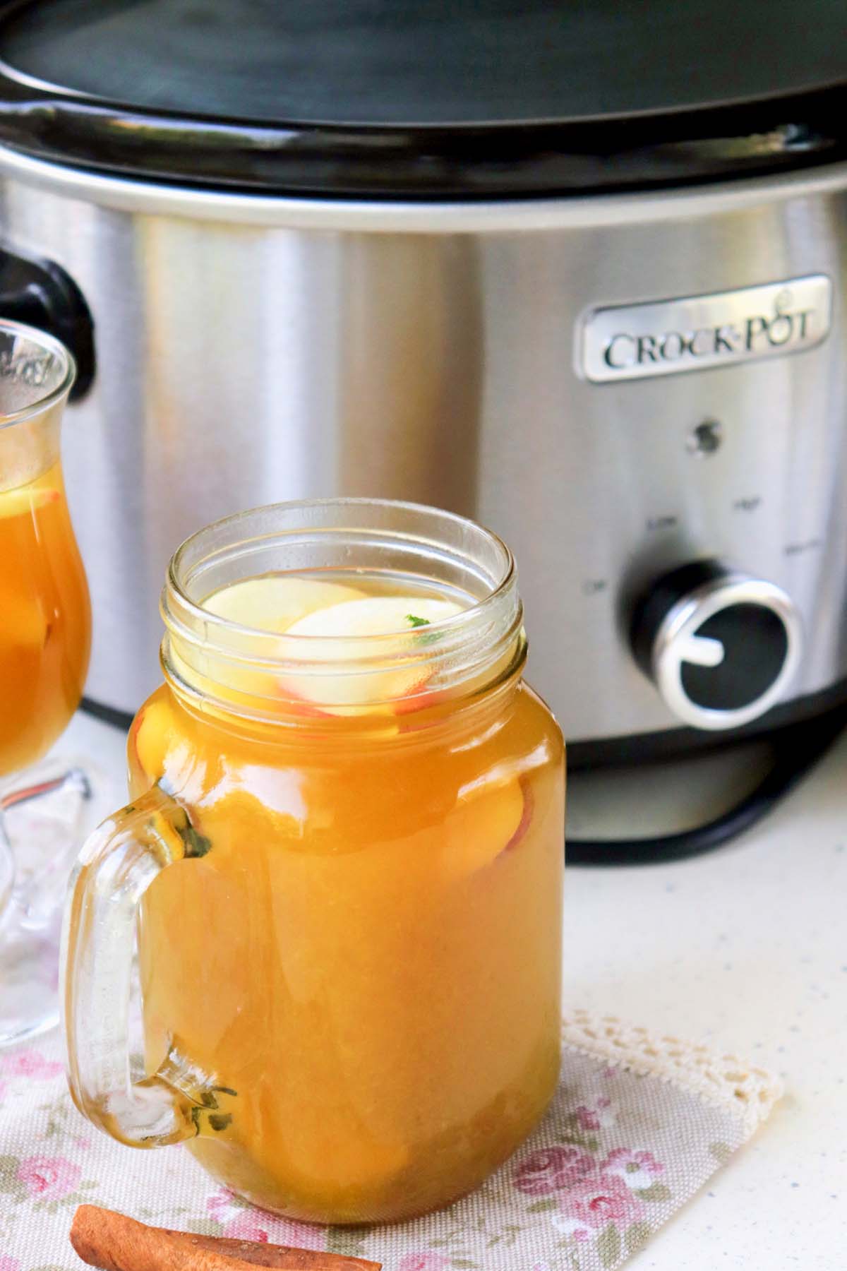 Cider in a glass topped with apple slices.