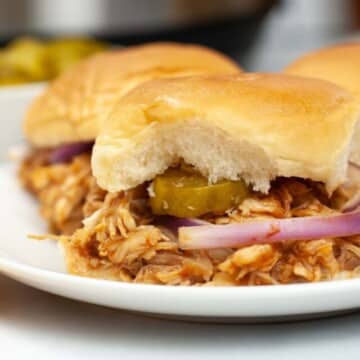Sliders topped with pickles and onion.
