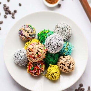 Truffles rolled in toppings on a white plate.