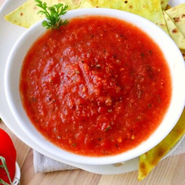 salsa in a bowl with tortilla chips on a plate.