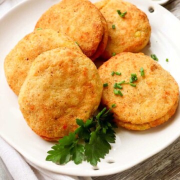 five potato patties on a plate.