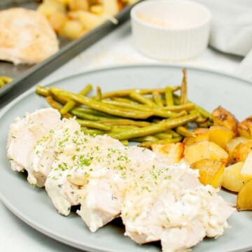 chicken, potatoes and green beans on a plate next to a baking sheet.