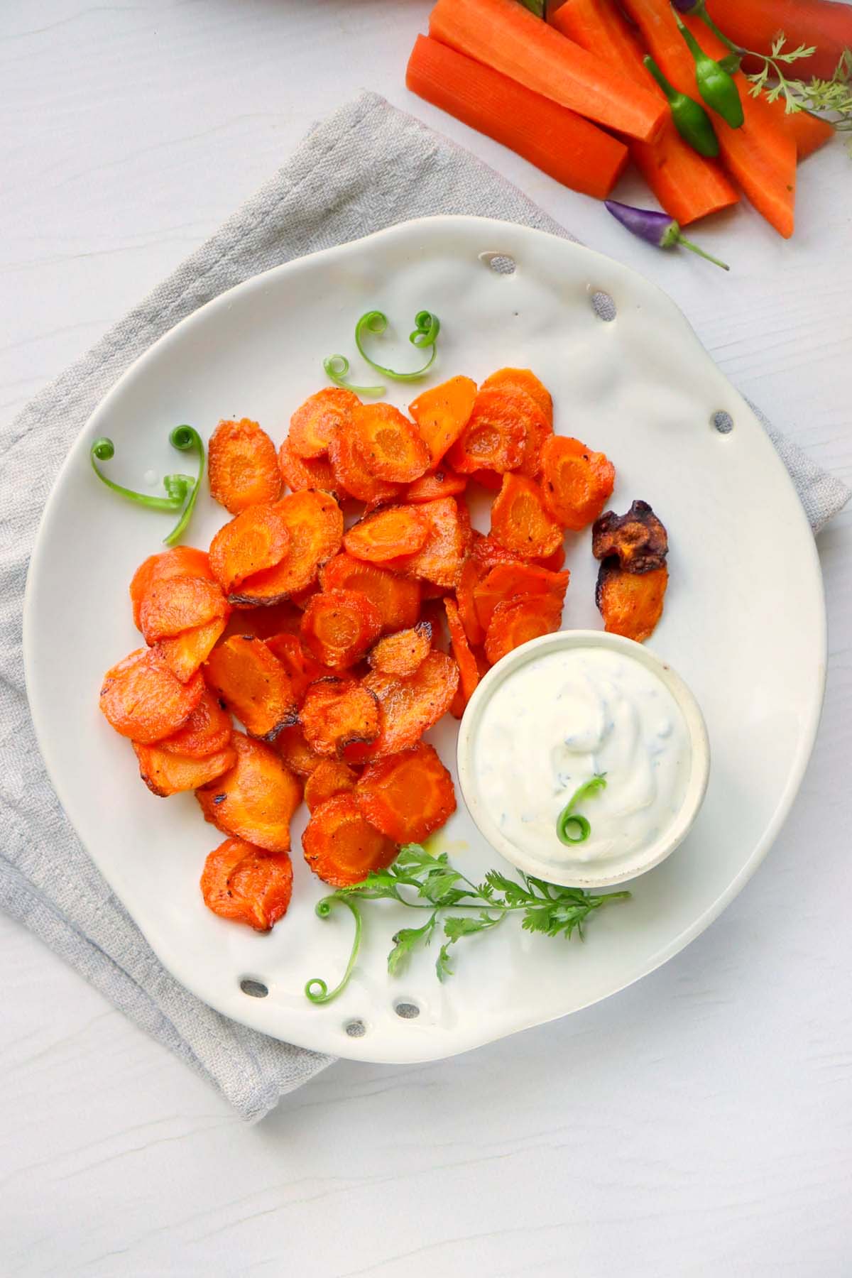 Carrot chips on a plate set on a kitchen towel.