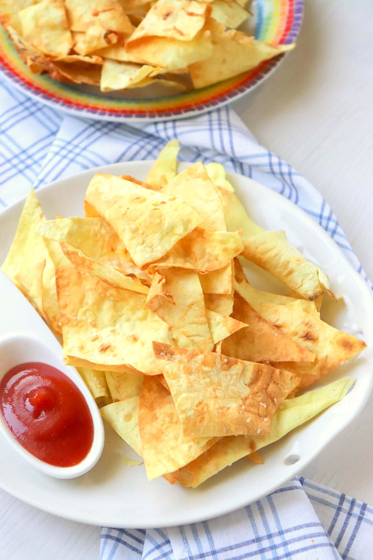 Two plates of chips set on a kitchen towel.