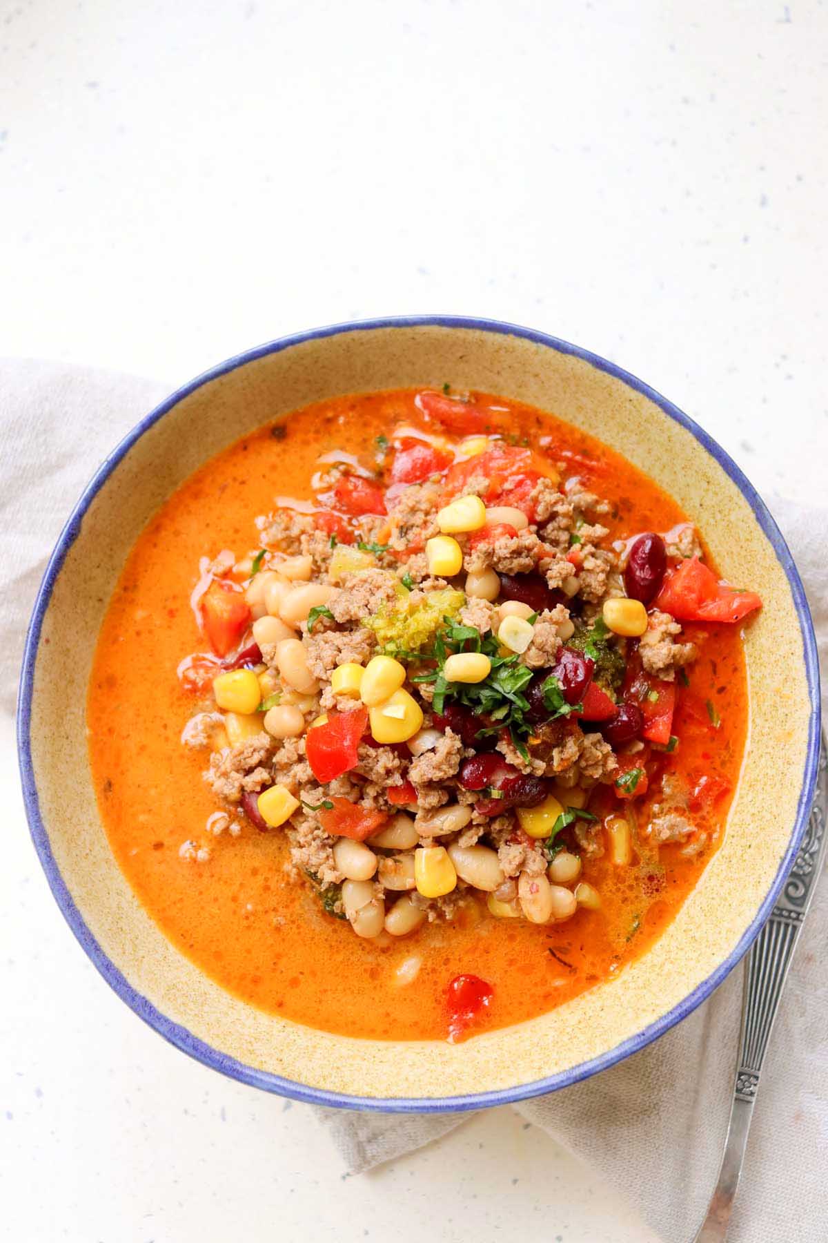 Soup in a bowl next to a spoon.