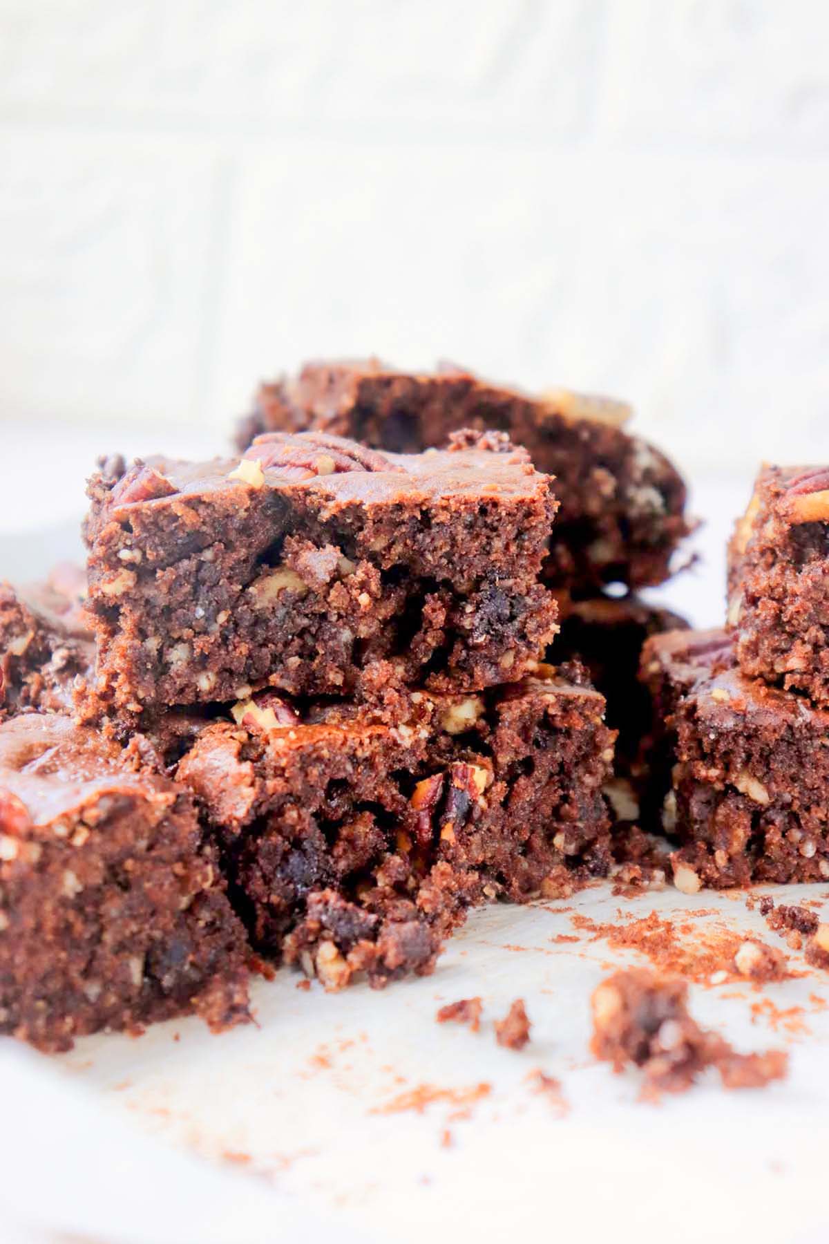 Brownies stacked on a piece of parchment paper.