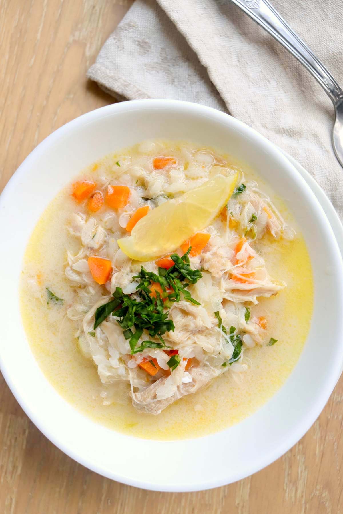 Chicken soup in a bowl topped with a lemon wedge.