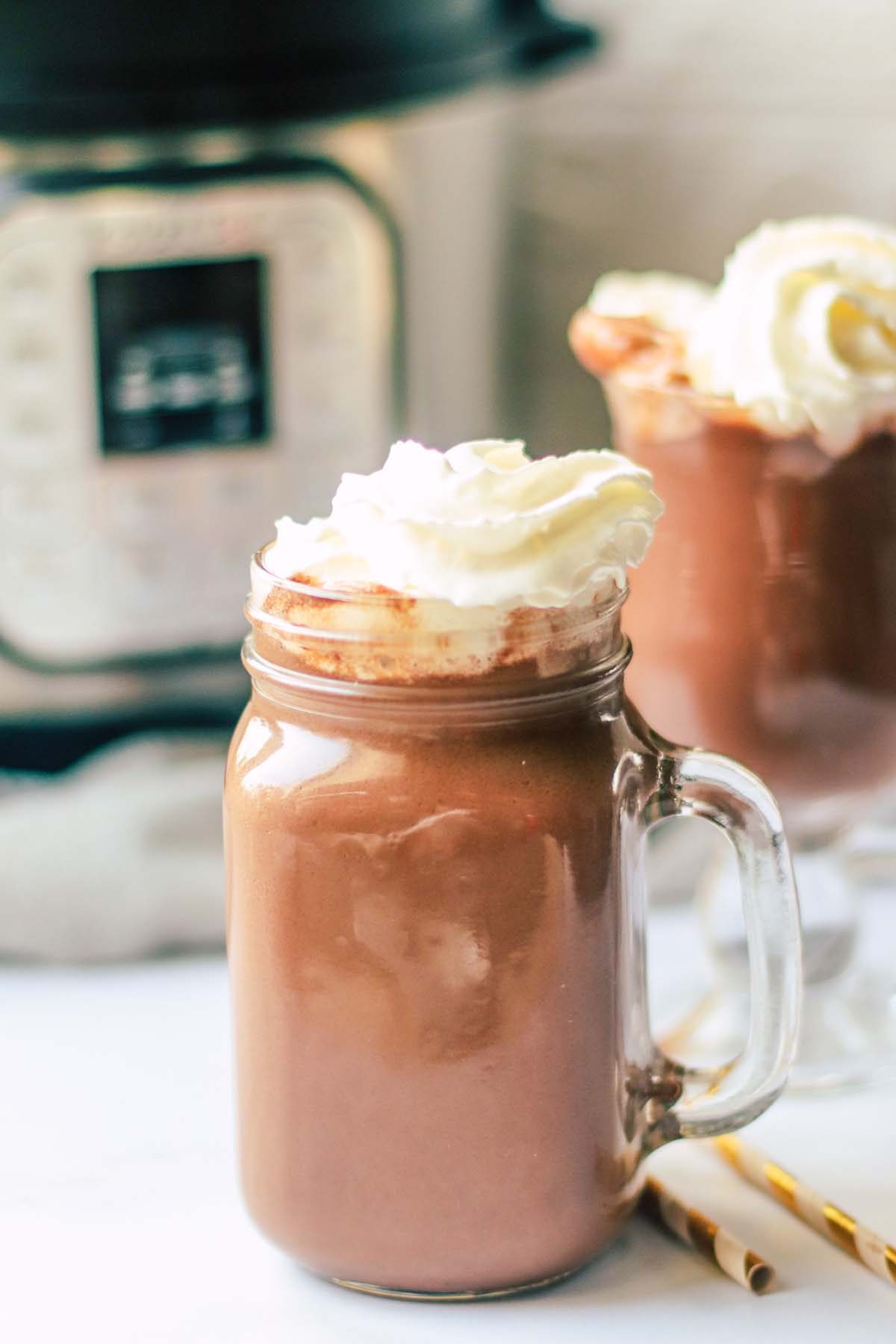 hot chocolate topped with whipped cream in front of the Instant Pot.