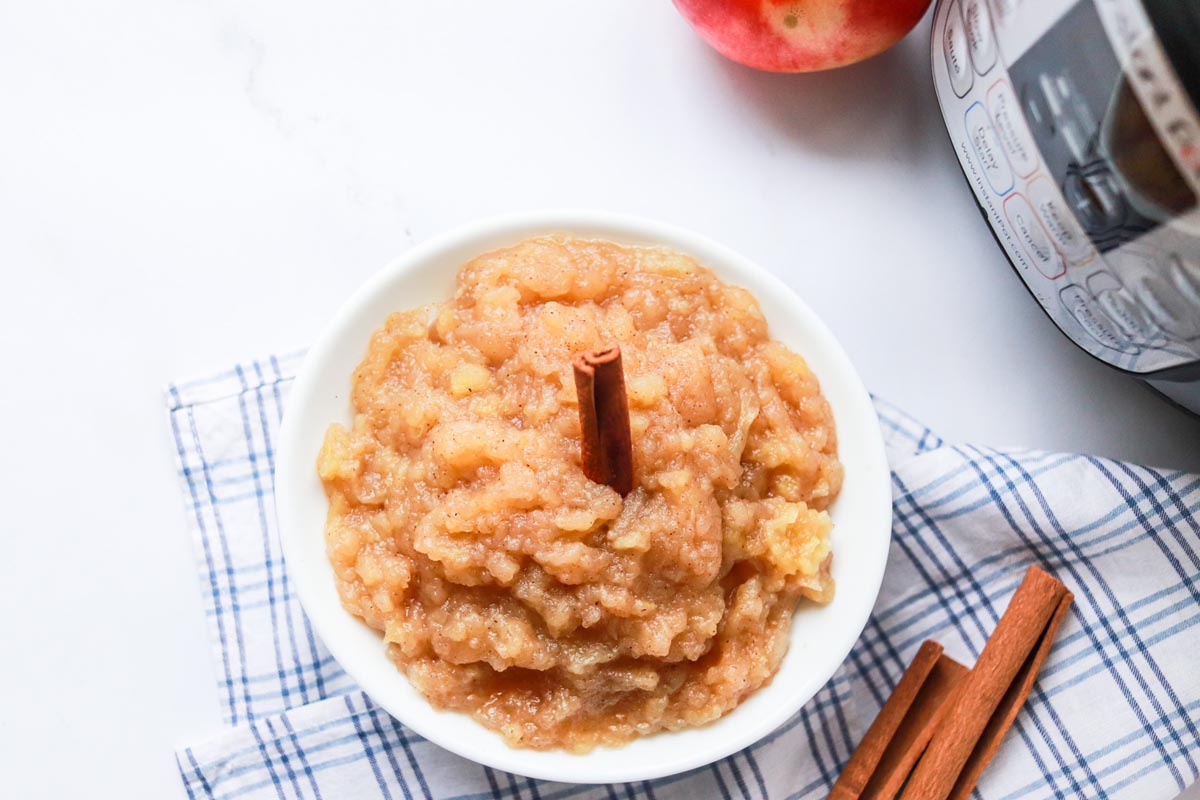 Applesauce in a bowl with a cinnamon stick inside.