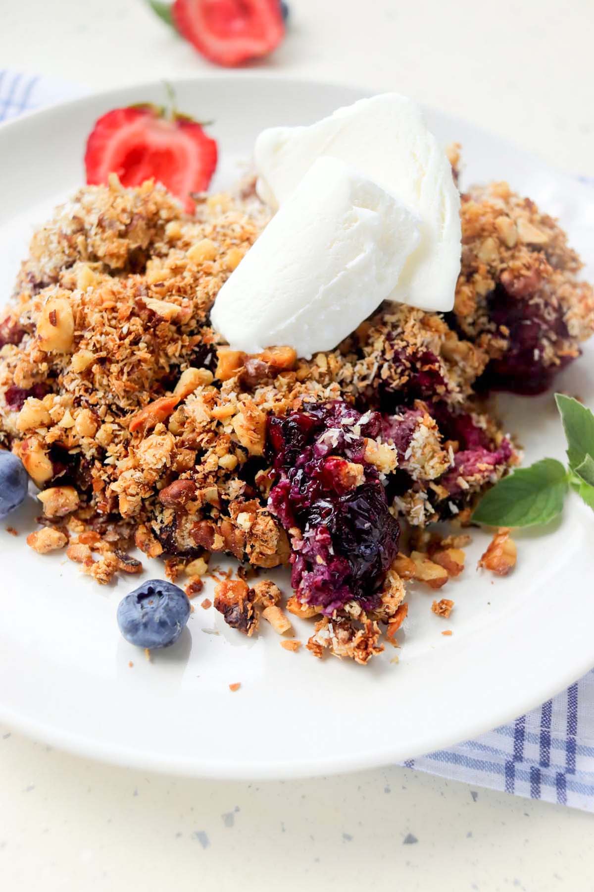 berry crumble on a plate topped with whipped cream.