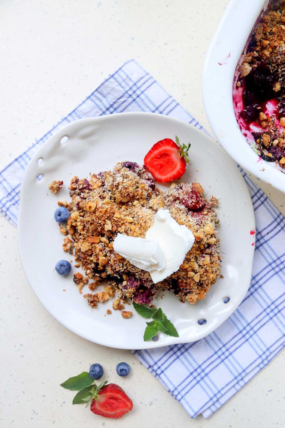top view of berry crumble on a plate with whipped cream.