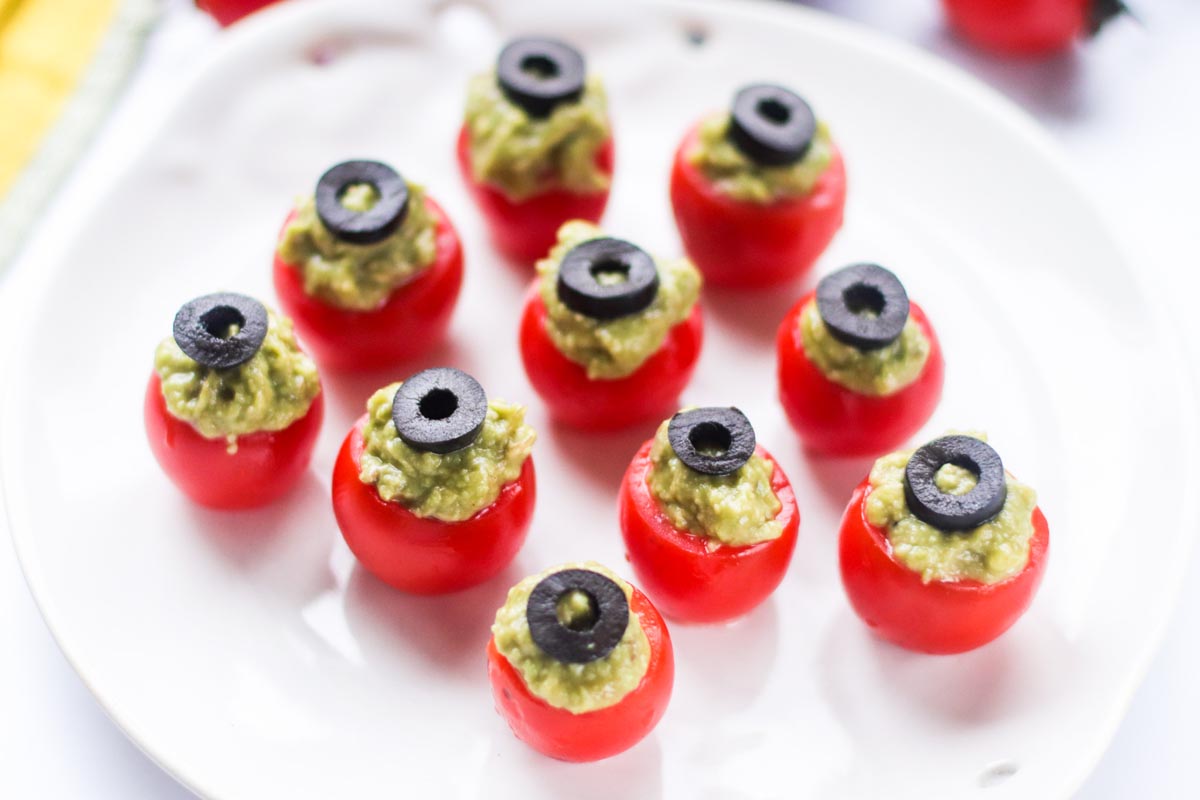 Guacamole stuffed inside cherry tomatoes and topped with a slice of black olive.