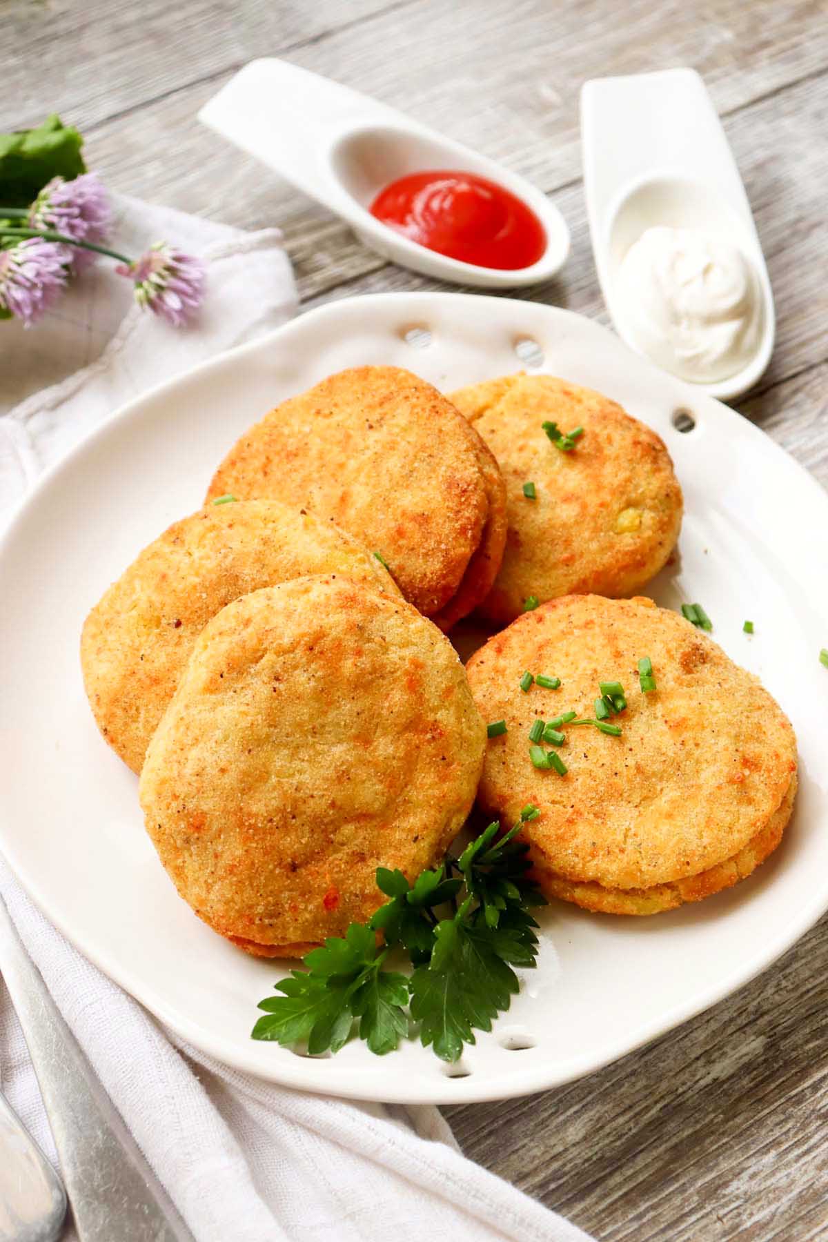 Five potato patties on a plate.