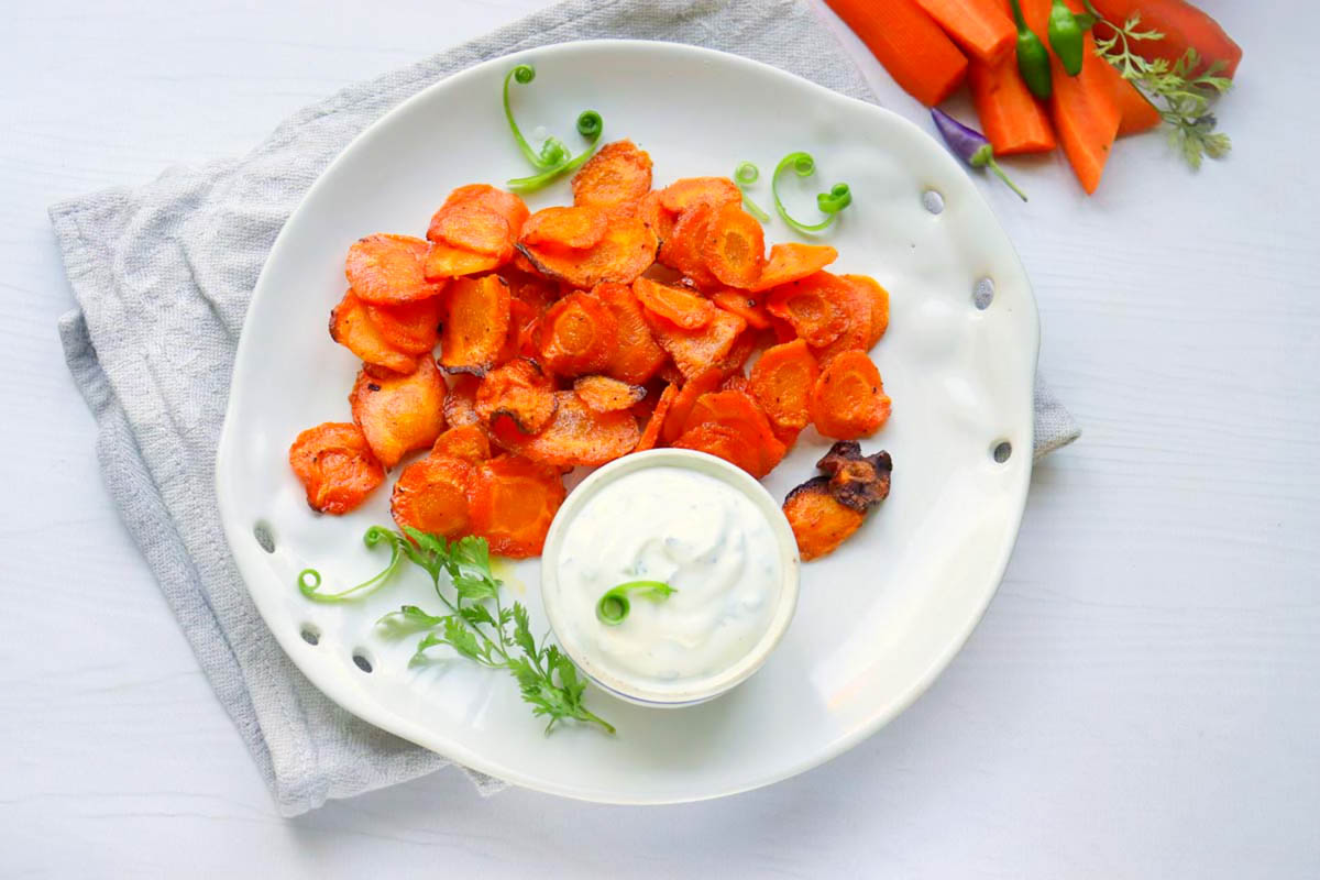 Carrot chips on a white plate with dipping sauce.