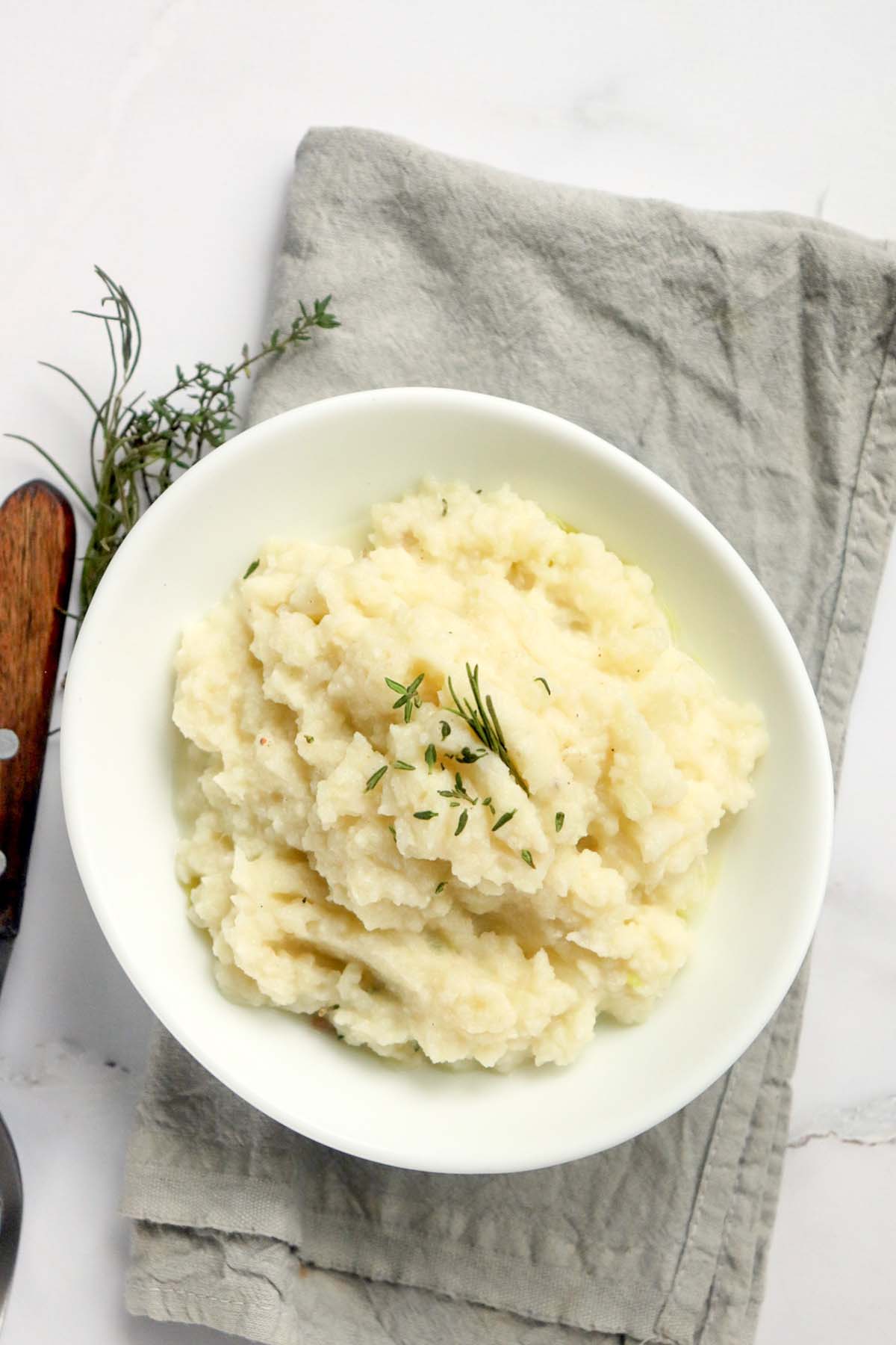 Mashed cauliflower in a bowl topped with dried parsley.