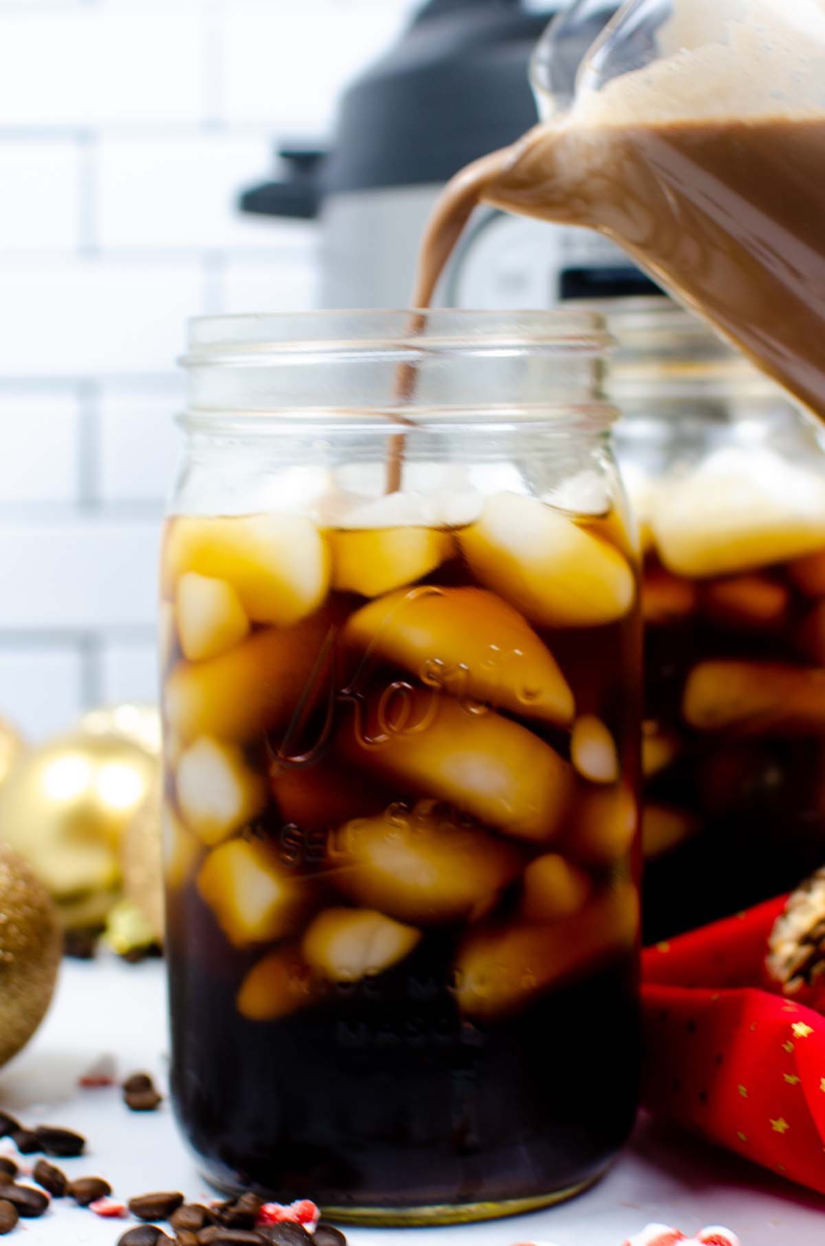 Creamer being poured into a glass of iced coffee.