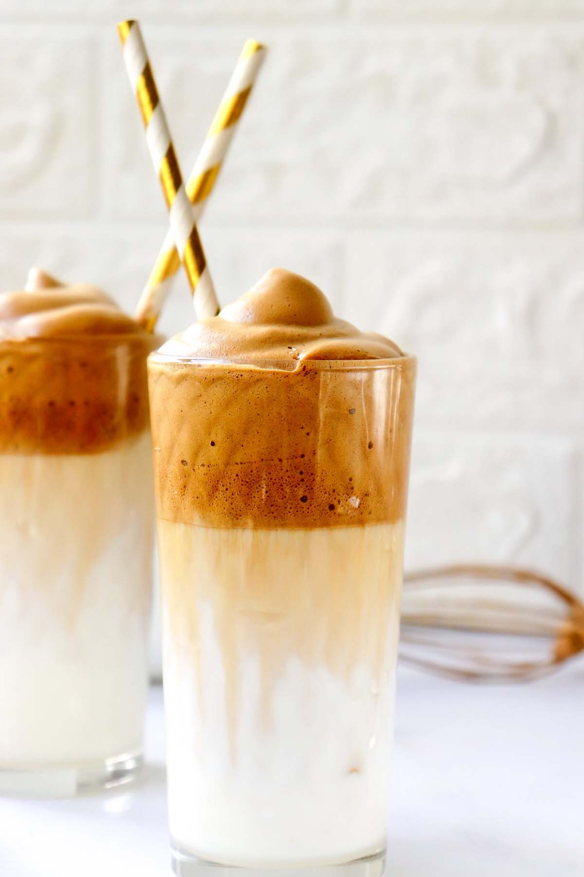 whipped coffee over milk in a glass with a straw.