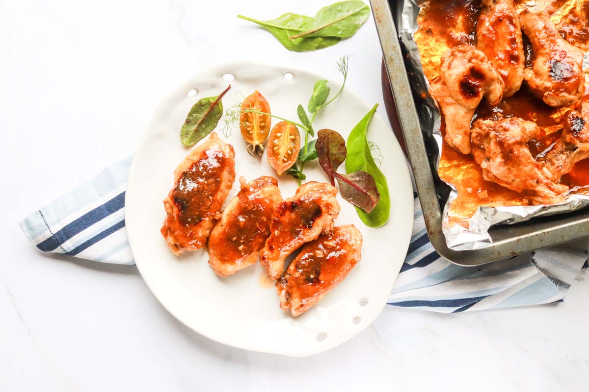 Wings on a plate next to the baking dish.