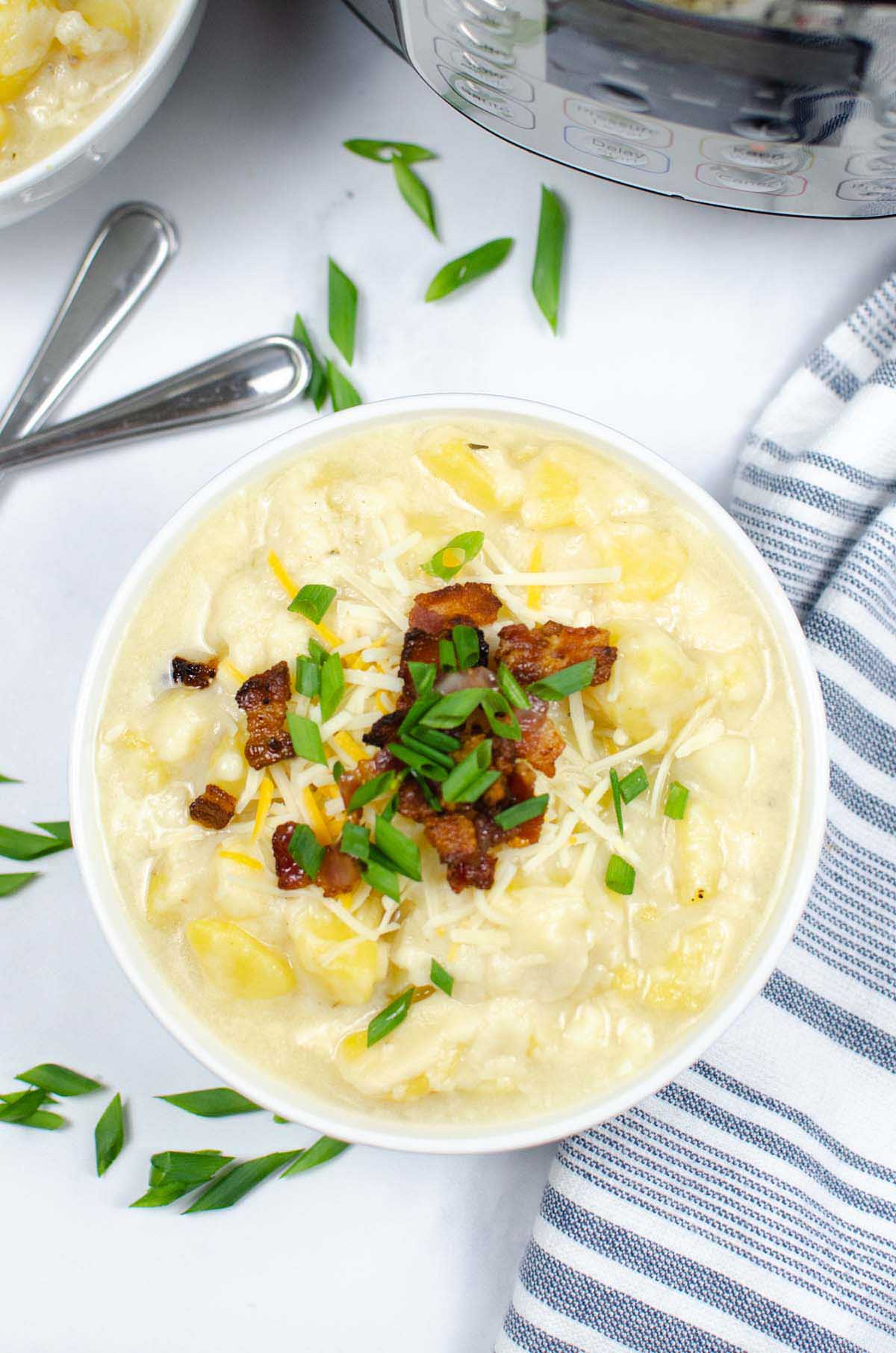 Potato soup in a bowl garnished with bacon and green onions.