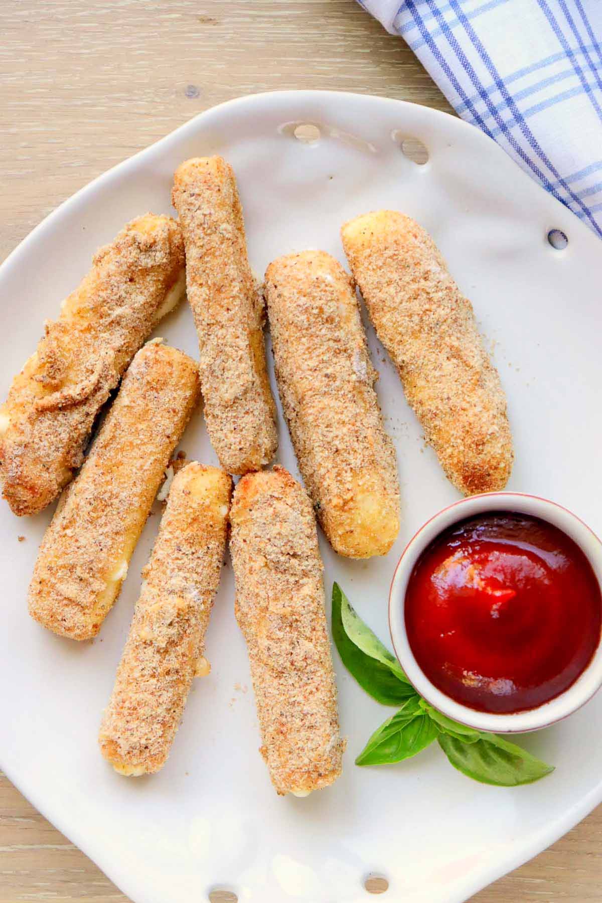 Mozzarella sticks on a plate with a dipping sauce.