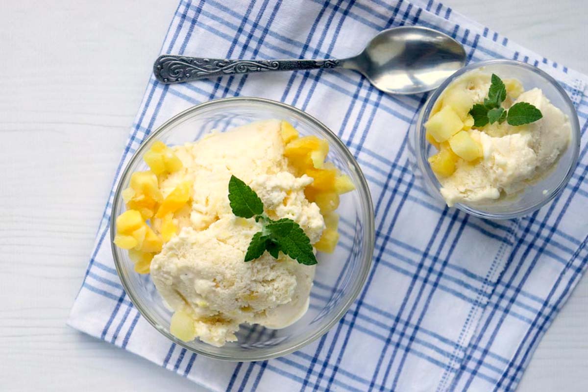 two bowls of mango nice cream with a spoon.