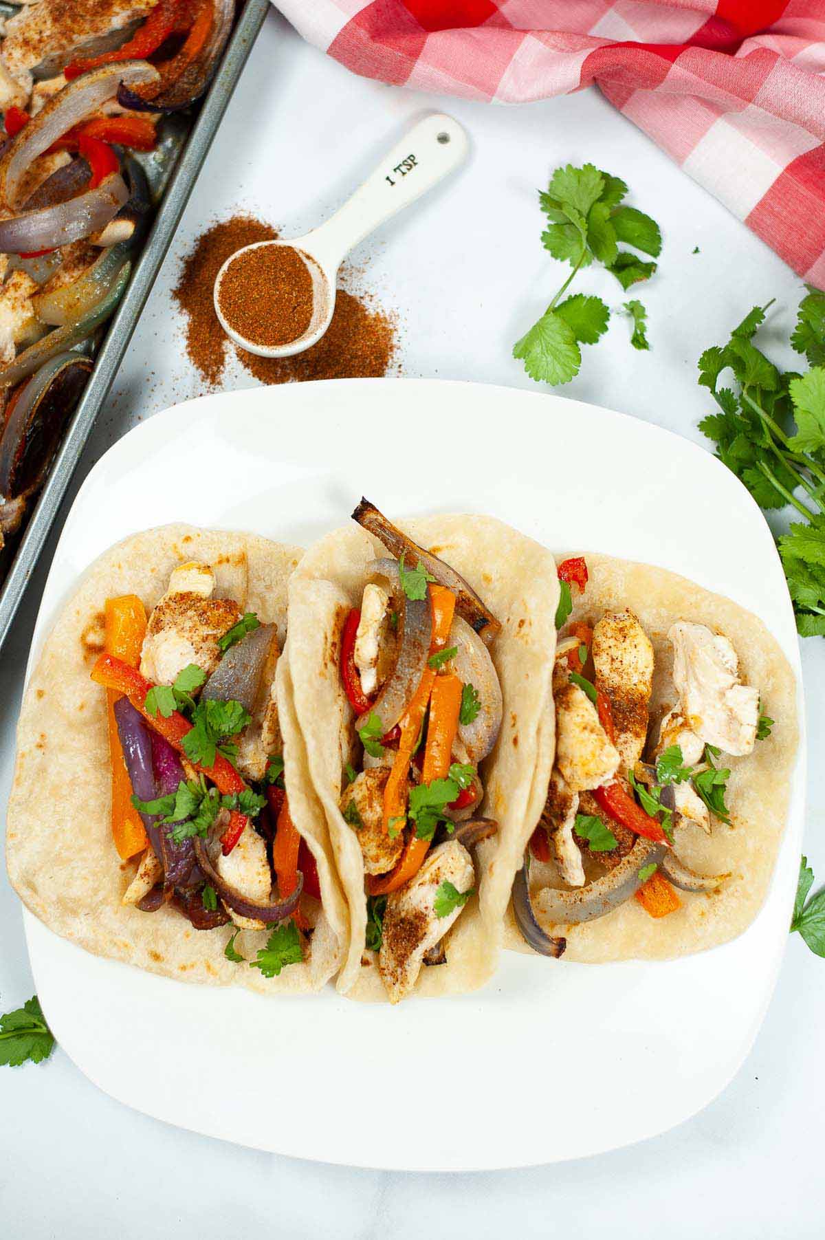 Tacos on a plate next to the sheet pan.