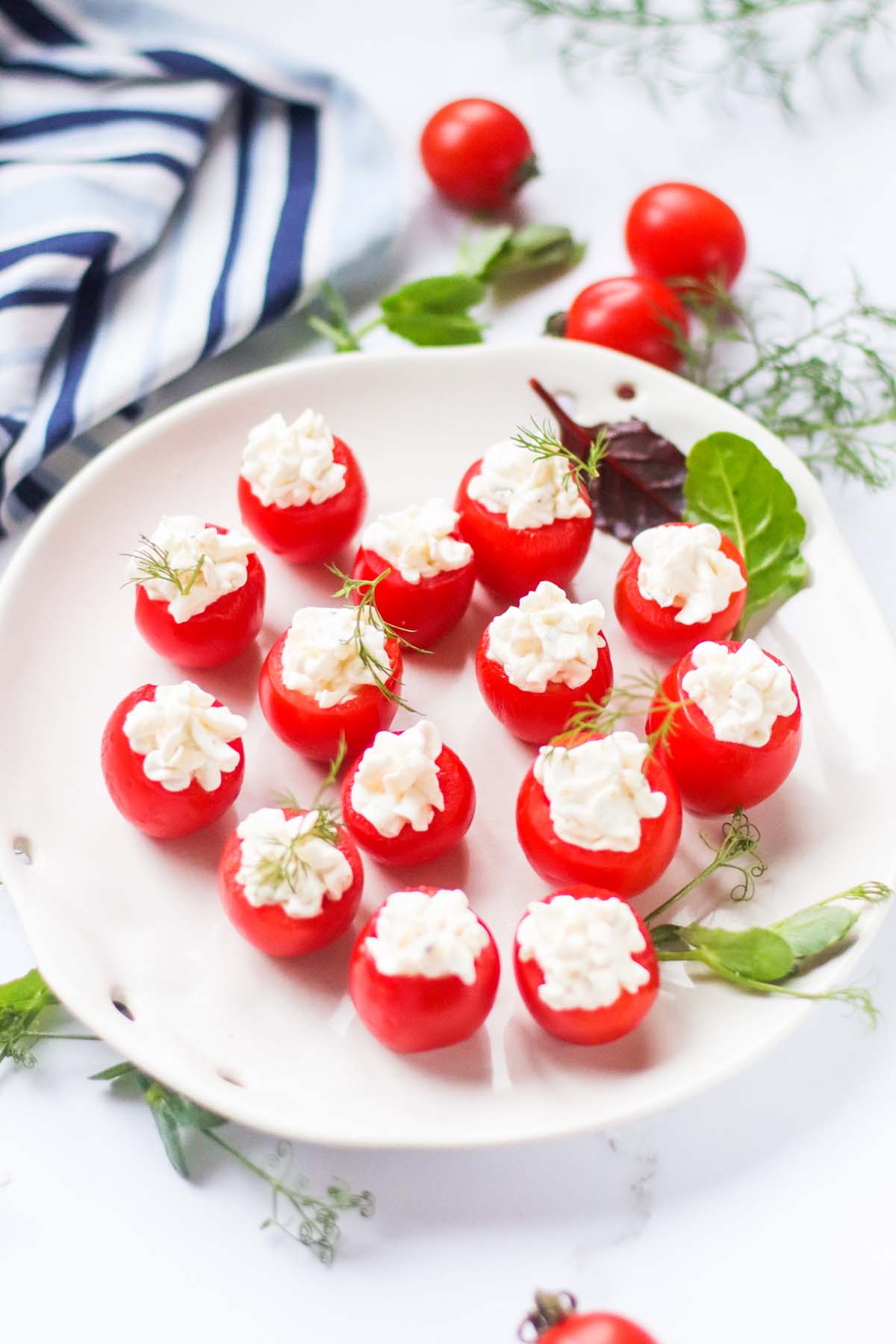 stuffed tomatoes on a plate with green herbs.