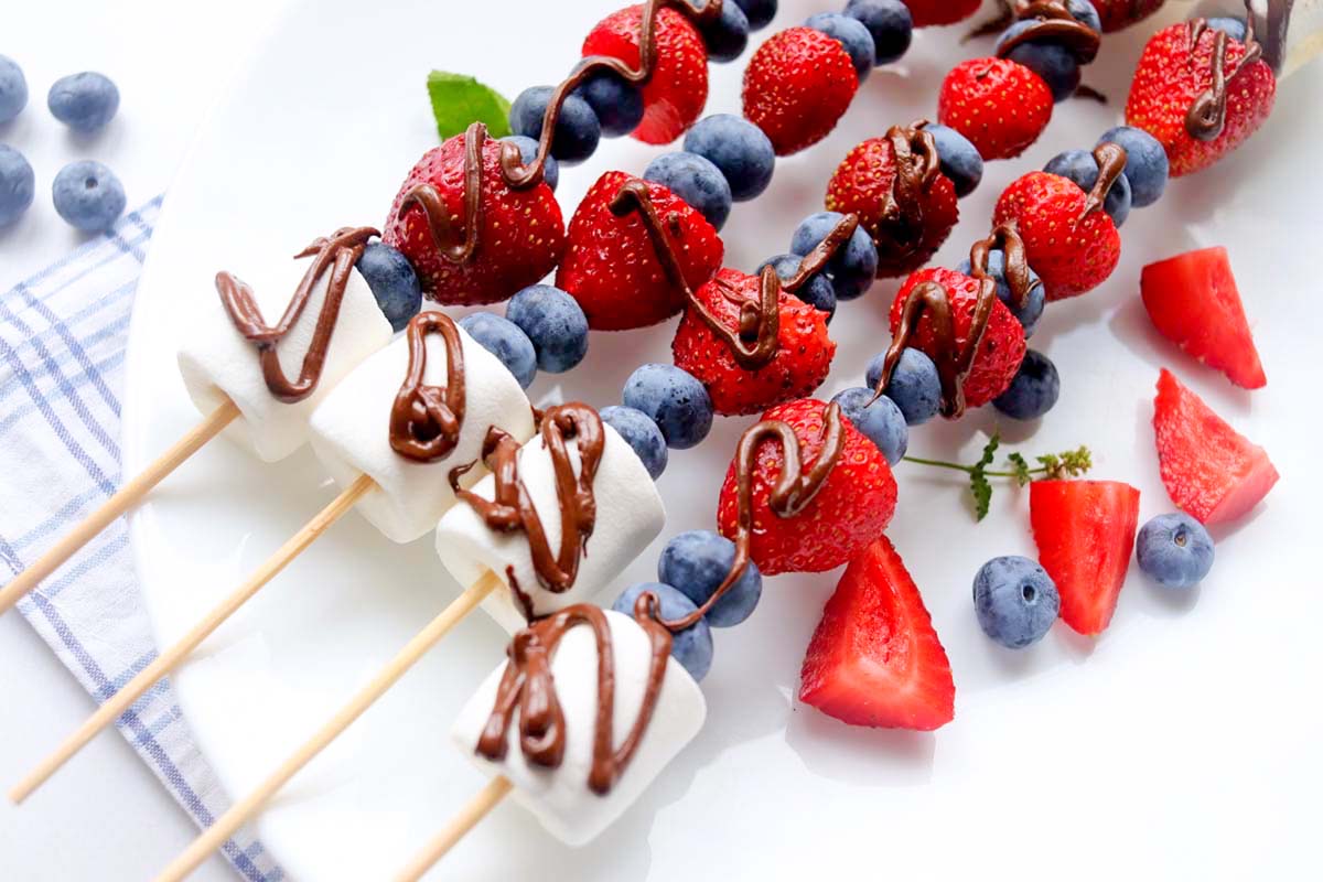 Fruit kabobs on a white plate.