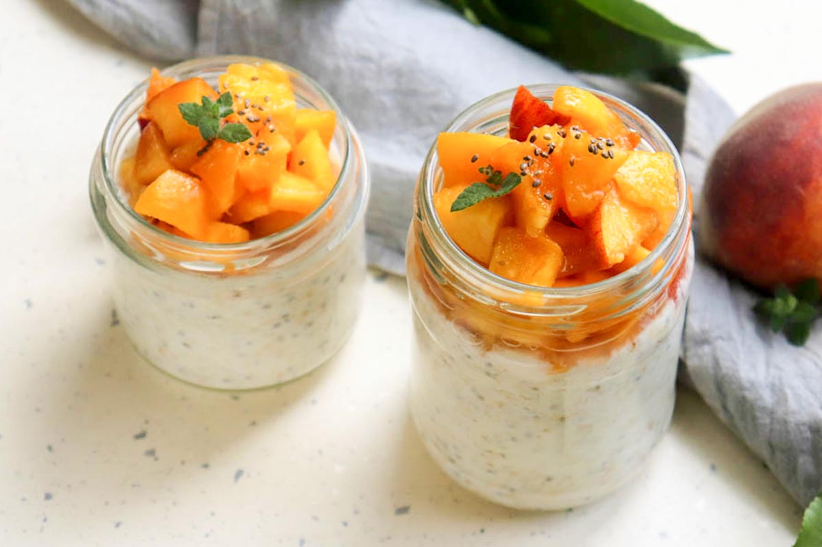 Two jars of oats topped with peaches.