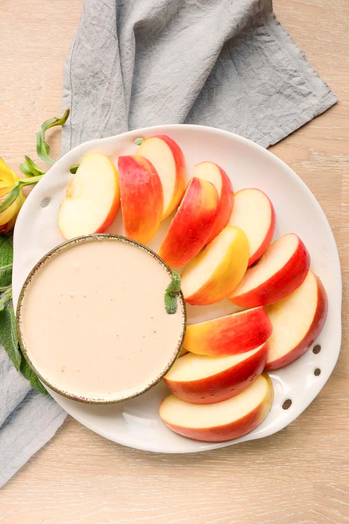 Yogurt dip and sliced apples on a plate.