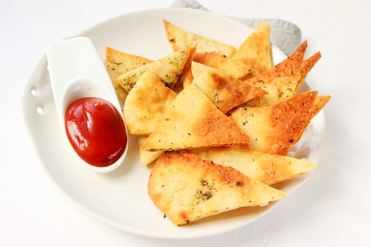 Pita chips on a plate with ketchup.