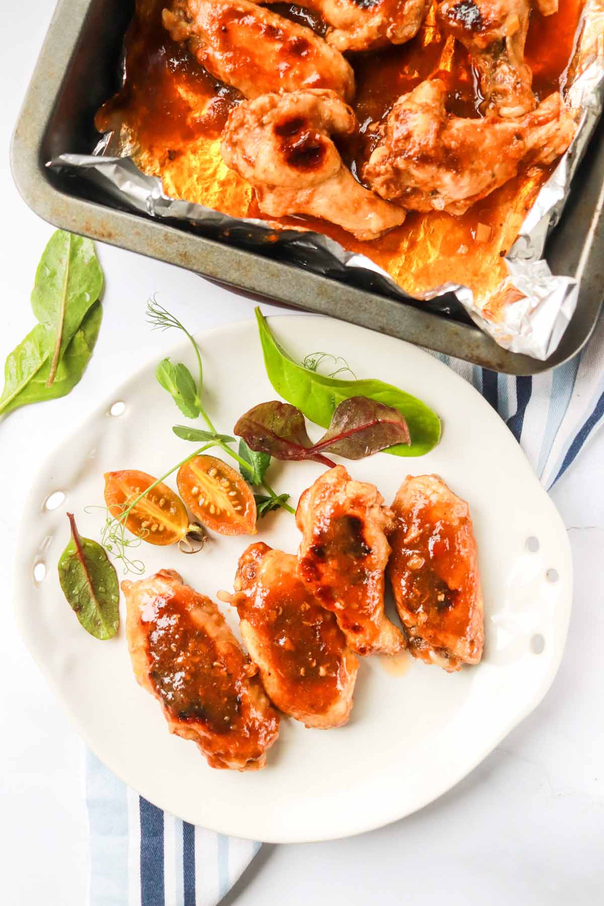 Plate of chicken wings next to a baking dish.