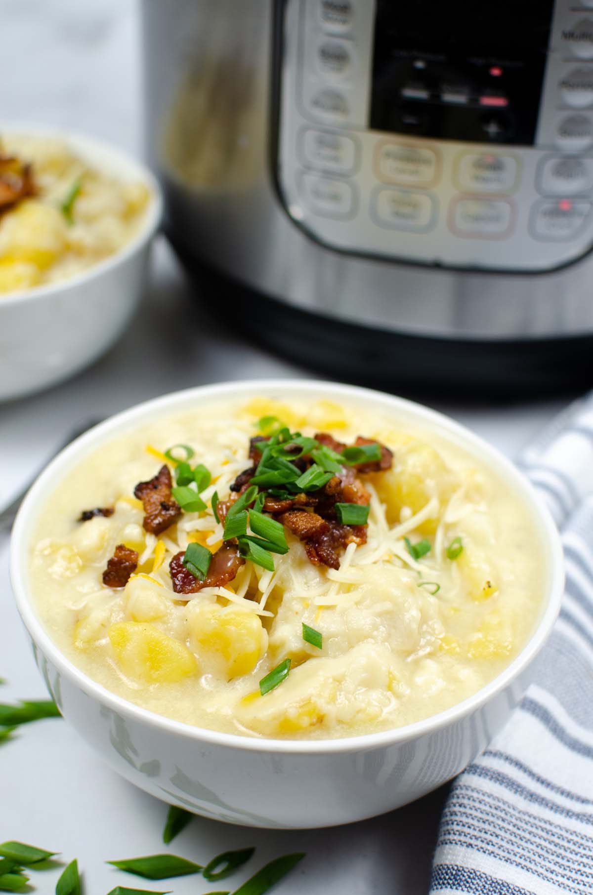A bowl of potato soup in front of the Instant Pot.