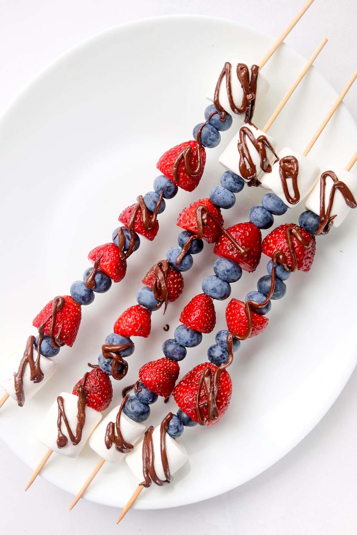 fruit kabobs on a white plate.