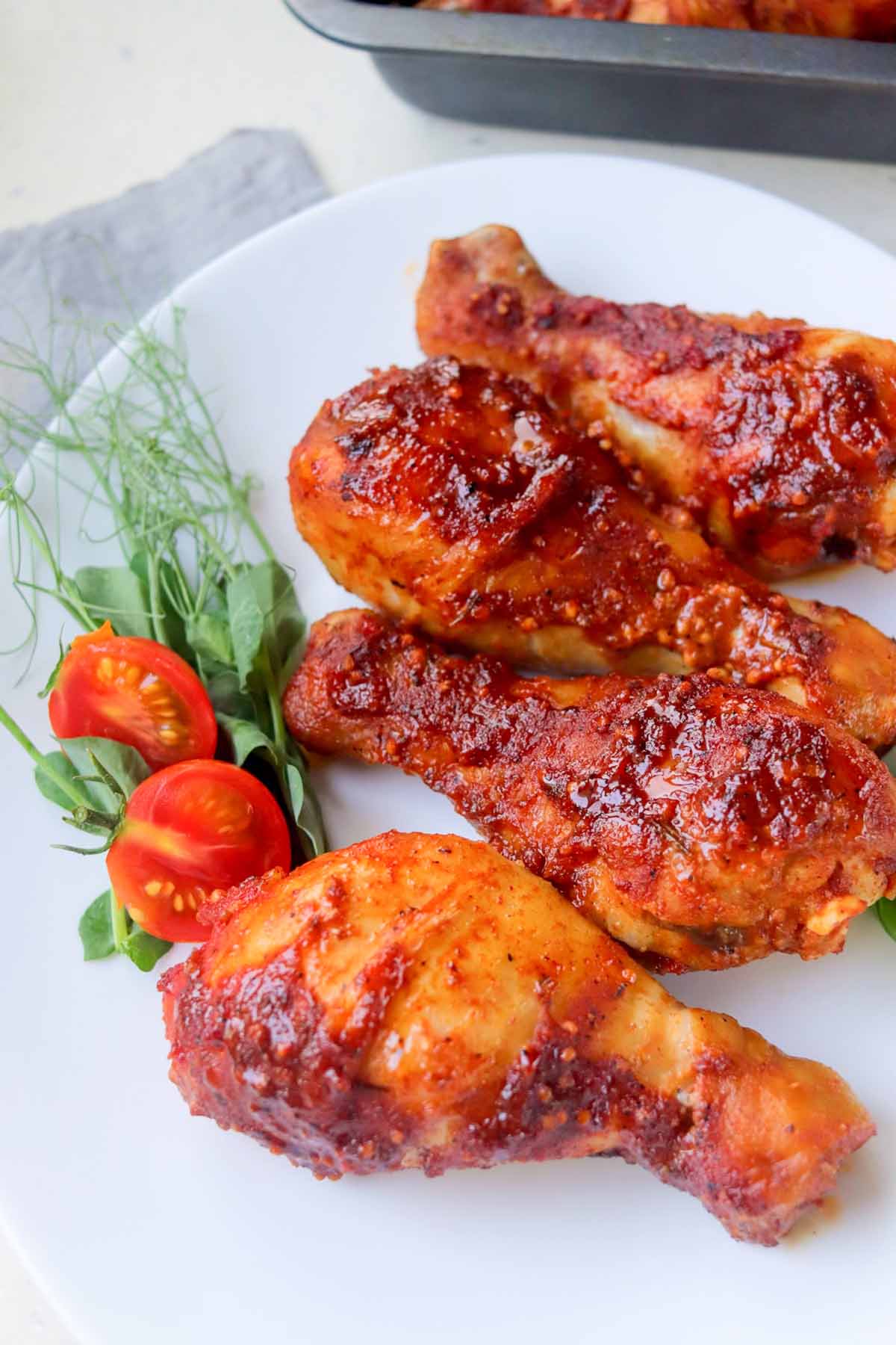 Four bbq chicken drumsticks on a plate.