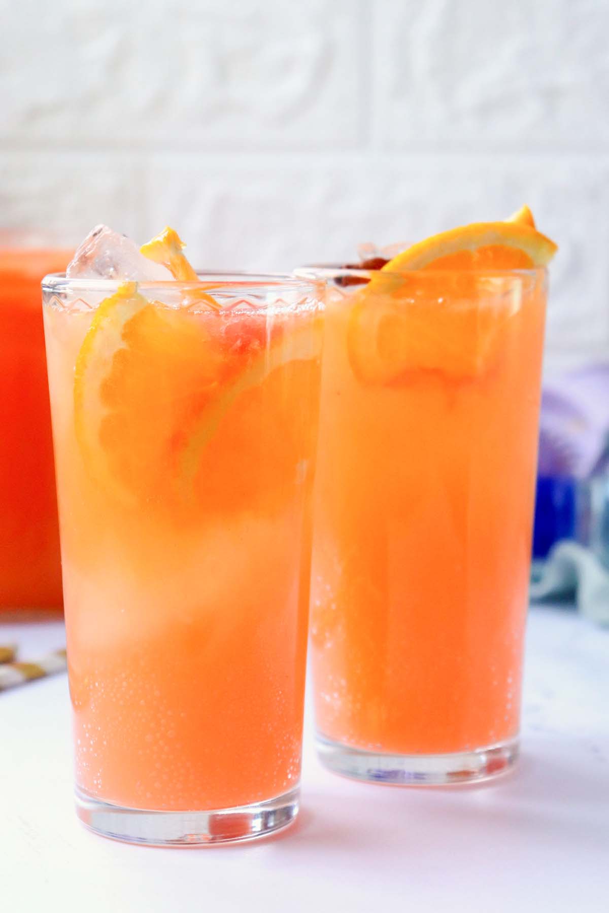 Citrus punch in two glasses topped with orange slices.