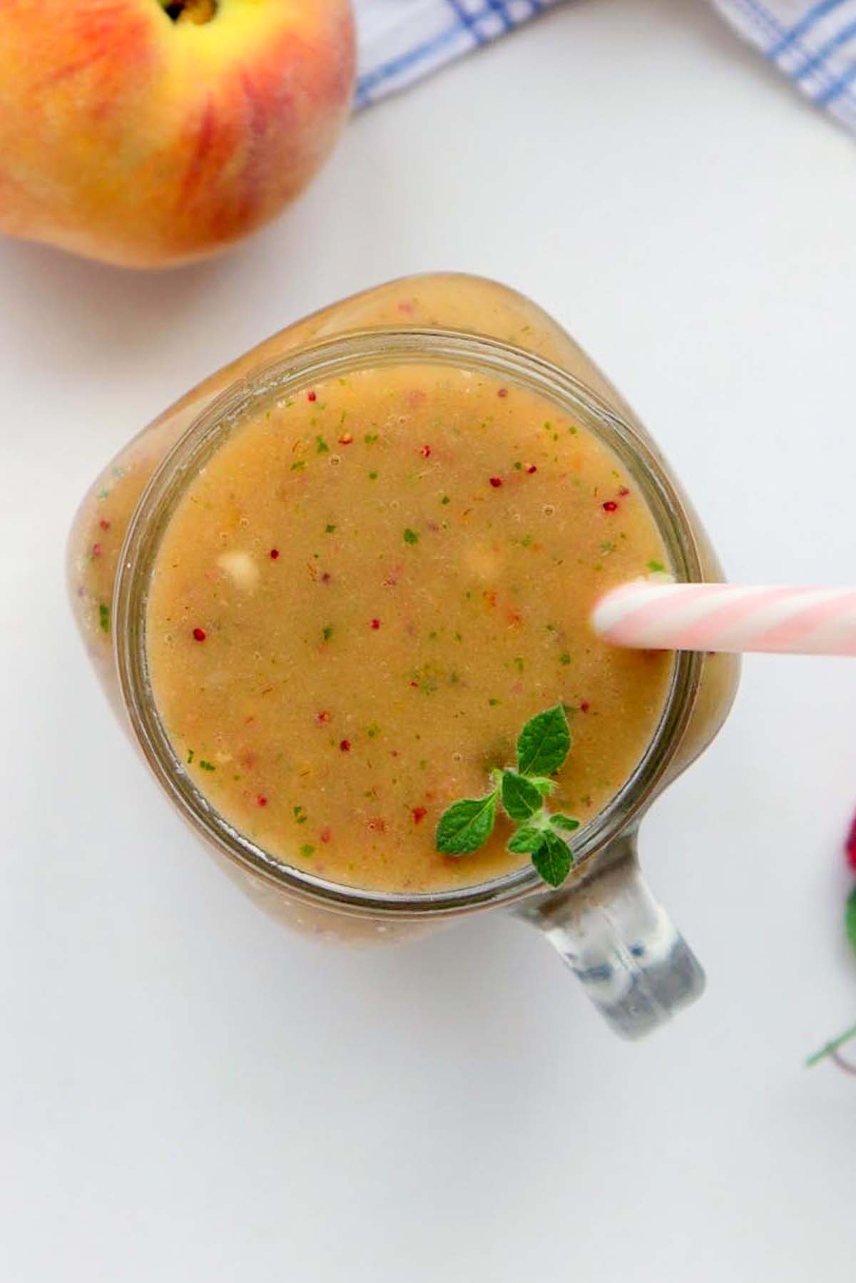 Smoothie in a jar with a straw, topped with a sprig of mint.