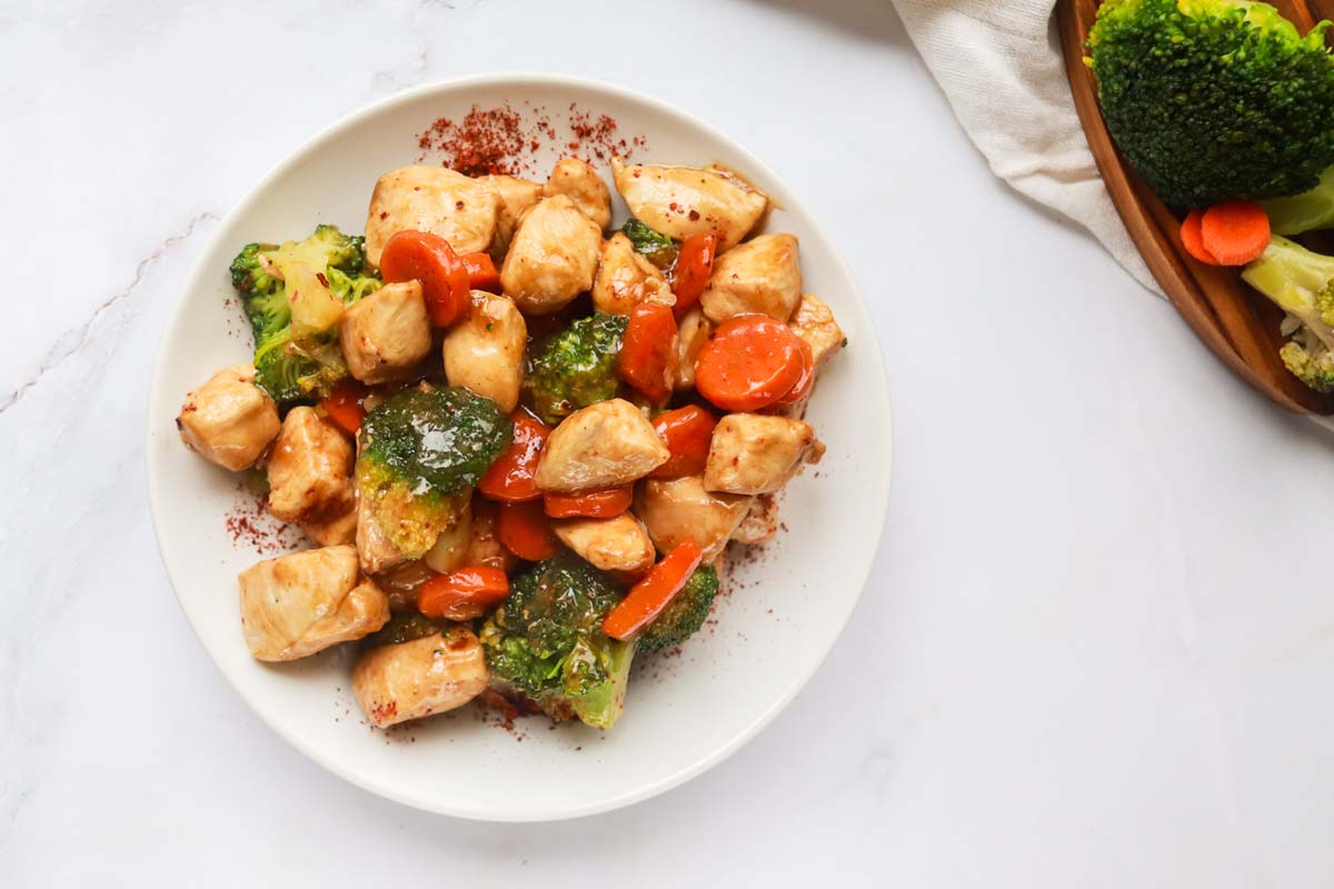 A plate of teriyaki chicken set on a white table.