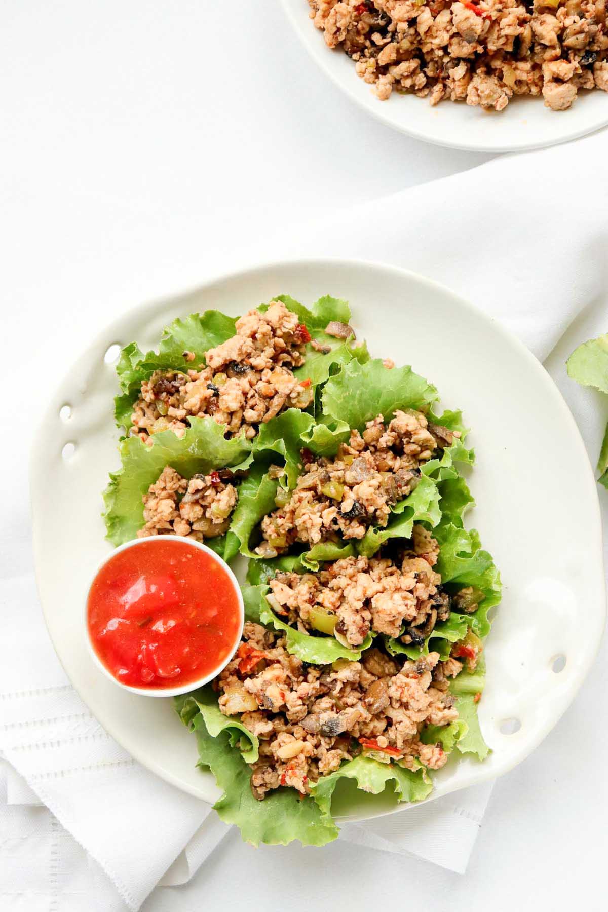top view of lettuce wraps on a plate with sauce.