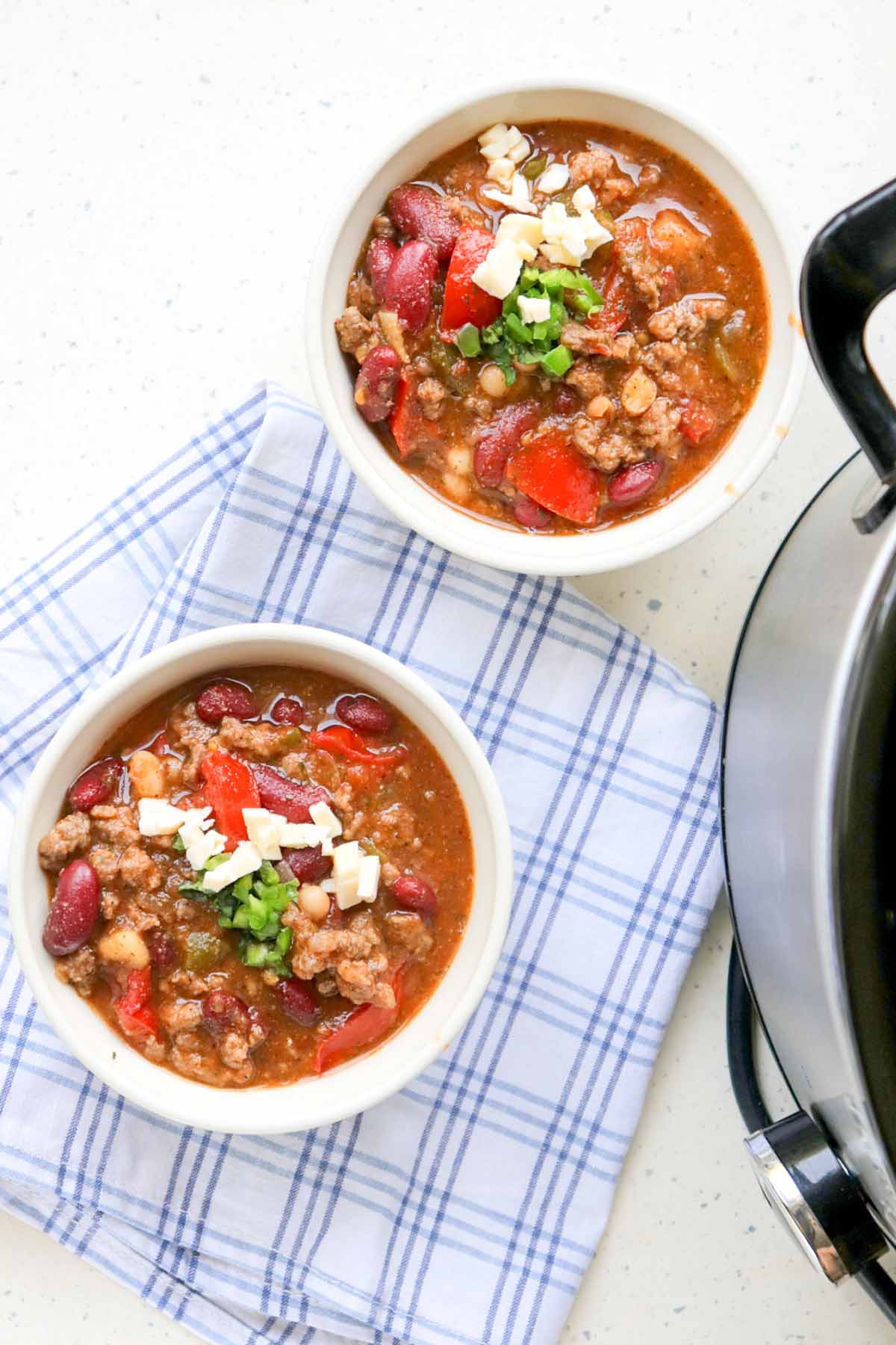 Two bowls of chili on a kitchen towel.