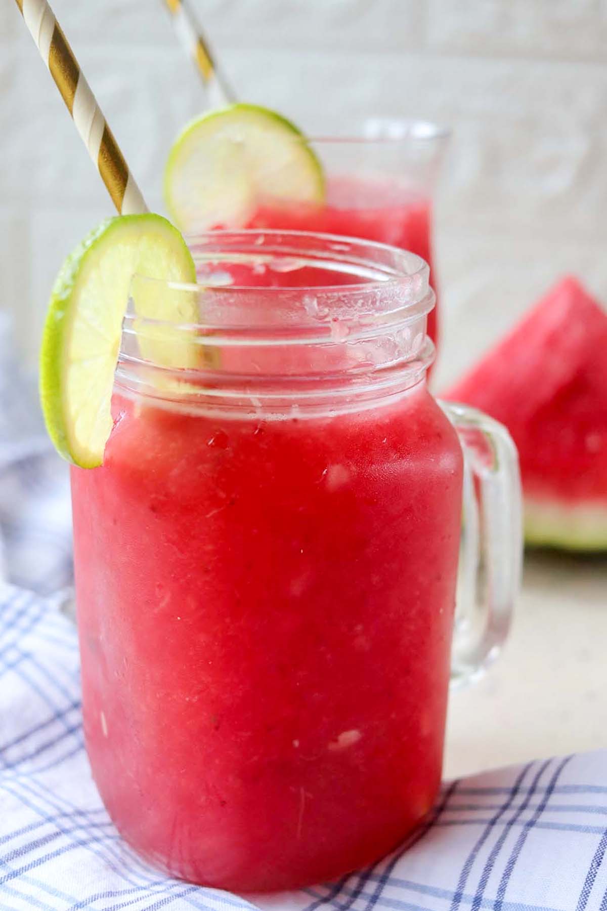 side view of watermelon slushy in a glass with a straw.