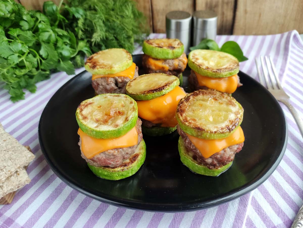 Sliders on a black plate on a purple and white kitchen towel.