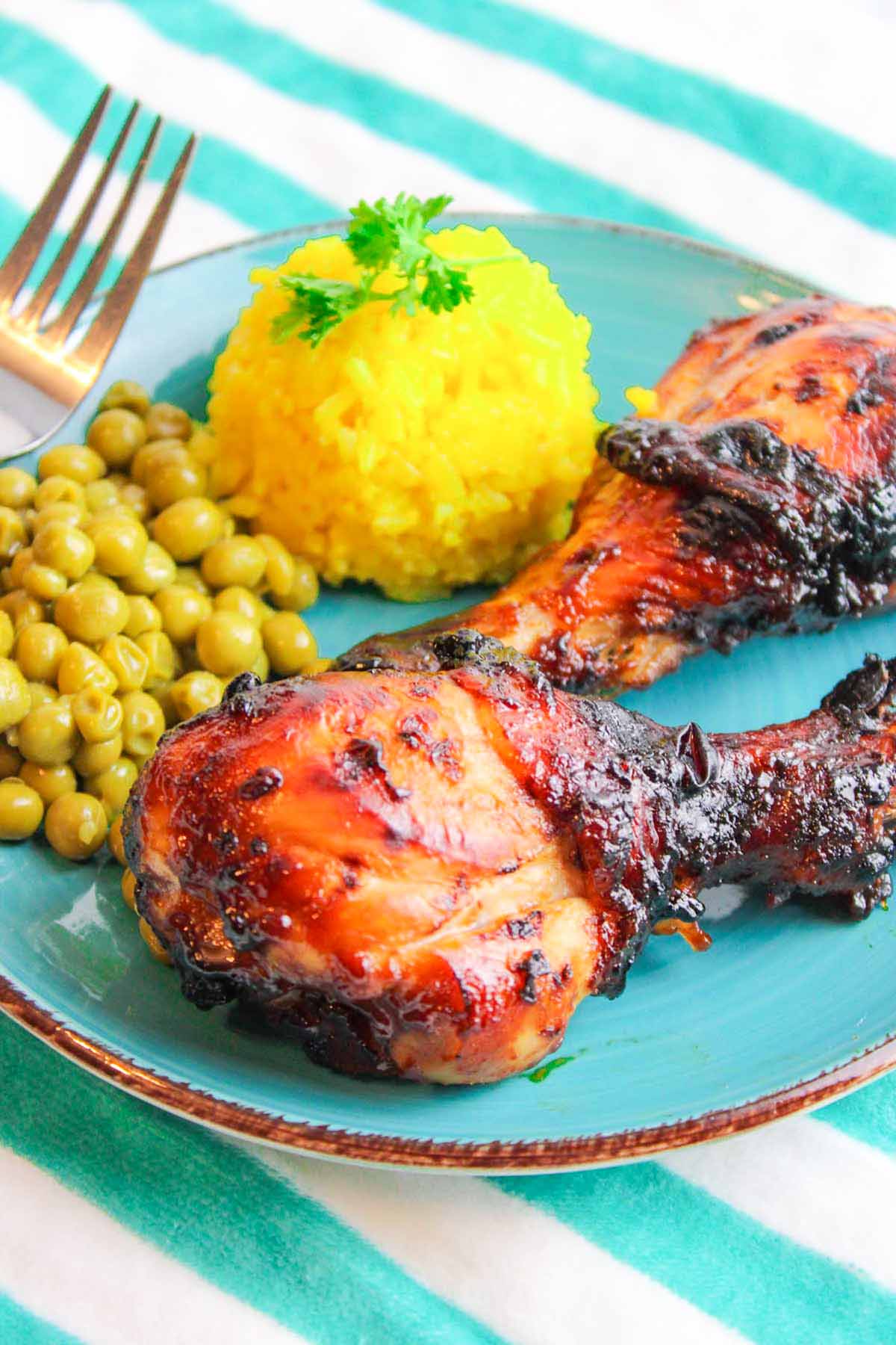 chicken drumsticks on a plate with rice and peas.