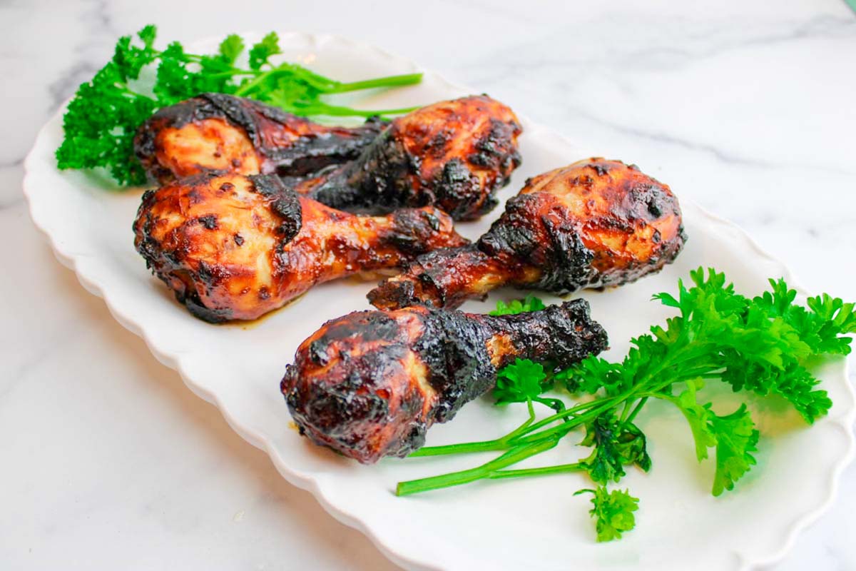 five chicken drumsticks on a plate.