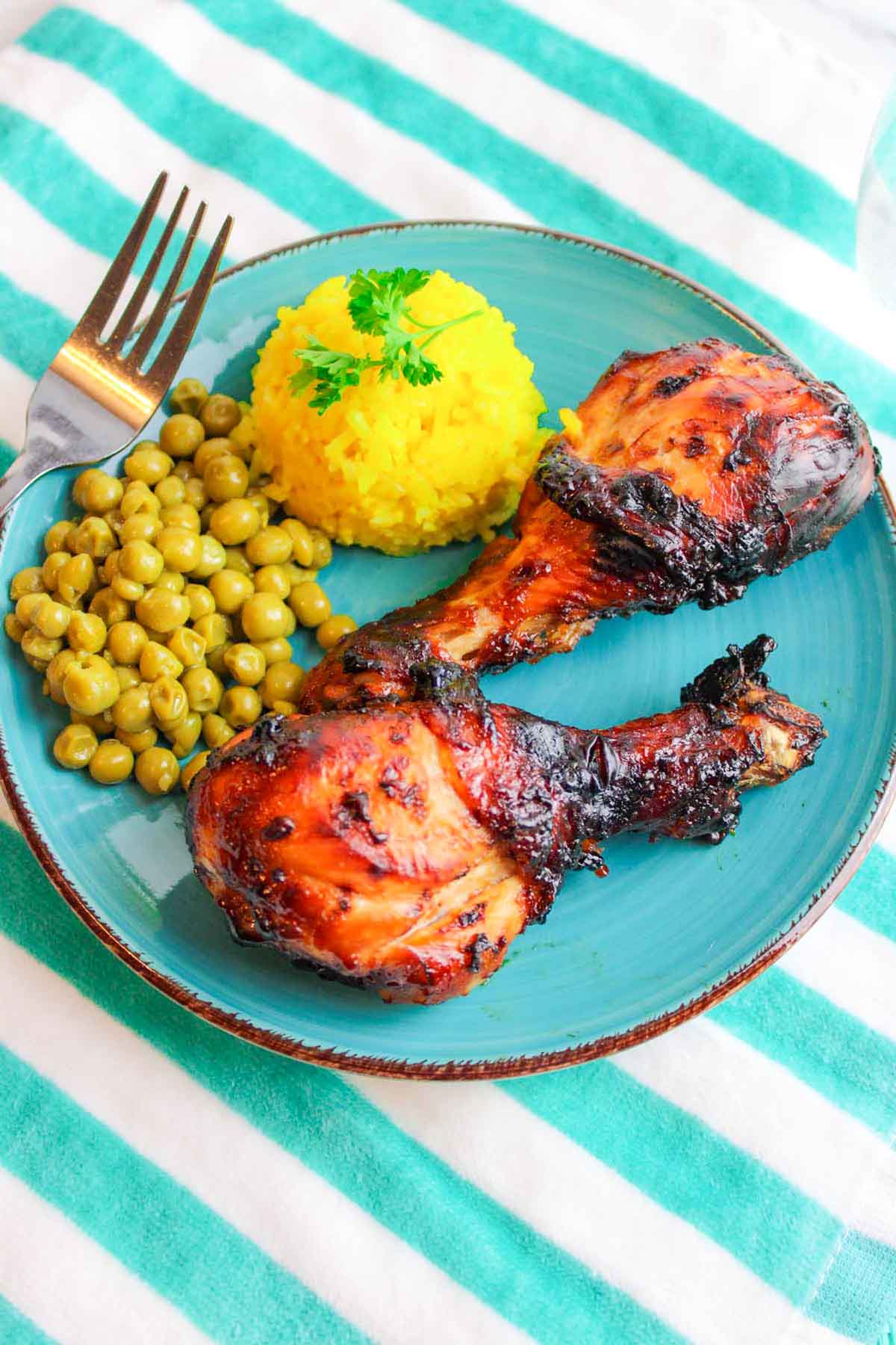 two bbq chicken drumsticks on a blue plate.