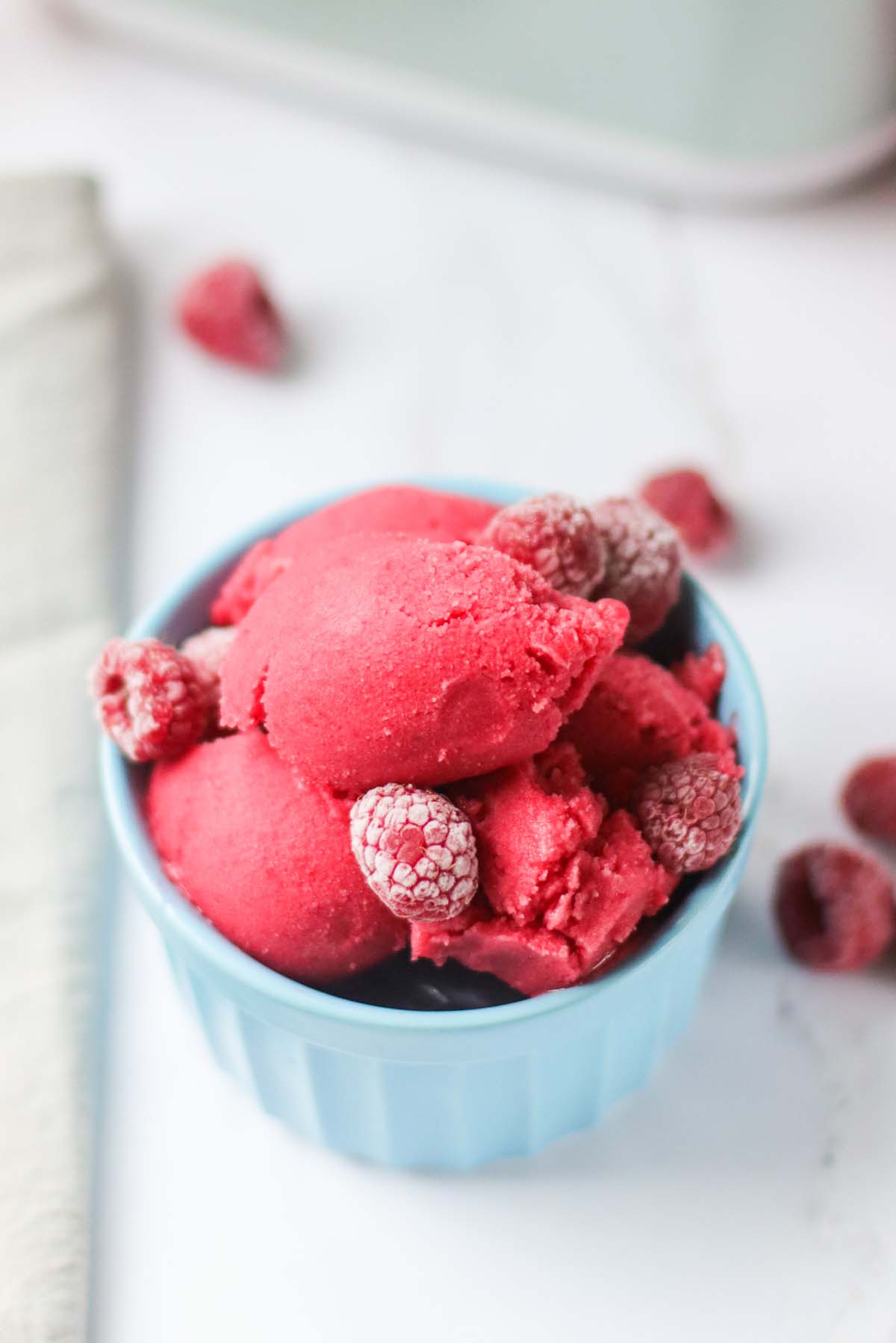 Raspberry sorbet in a bowl topped with raspberries.