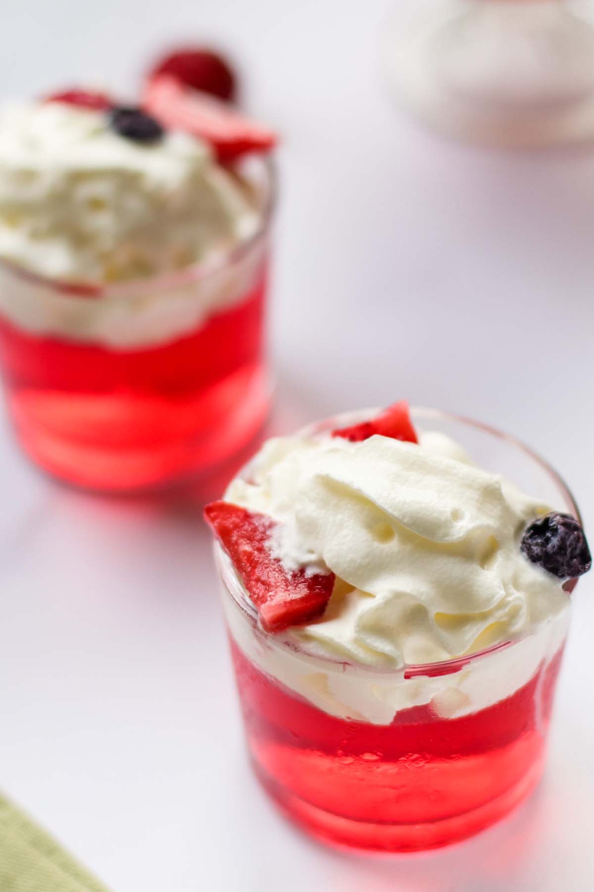 Two glasses of Jello on a white table.