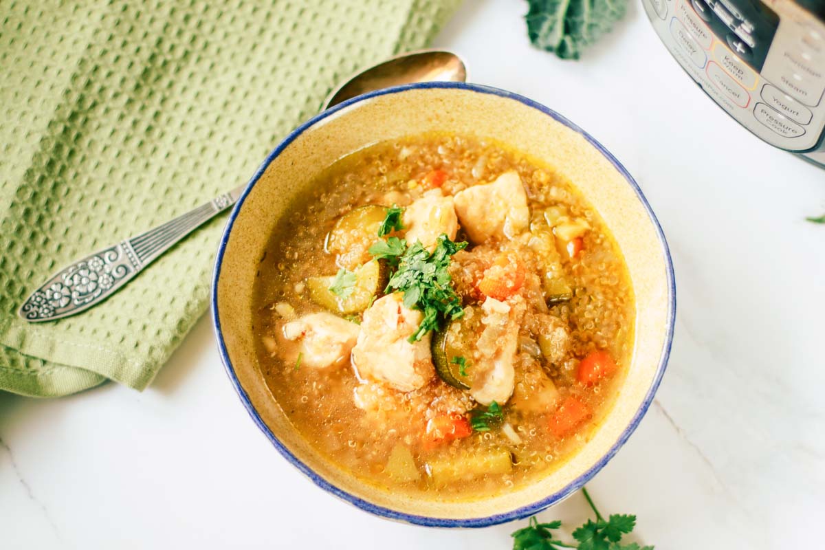 Quinoa soup in a bowl set next to a towel and spoon.