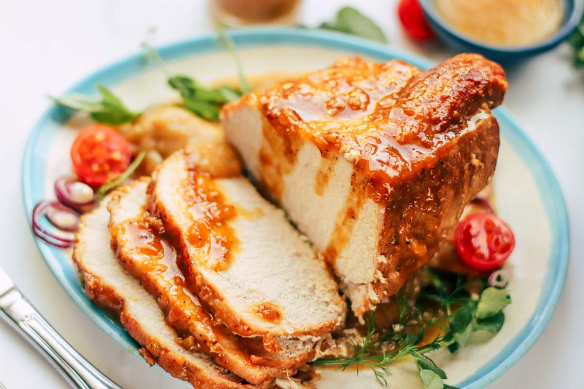 Sliced pork roast drizzled with sauce.